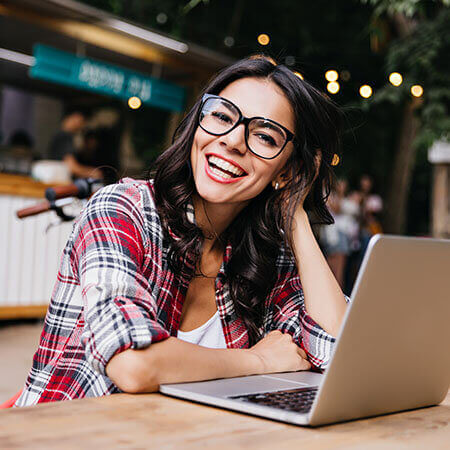 Ragazza sorridente seduta al bar con un computer portatile